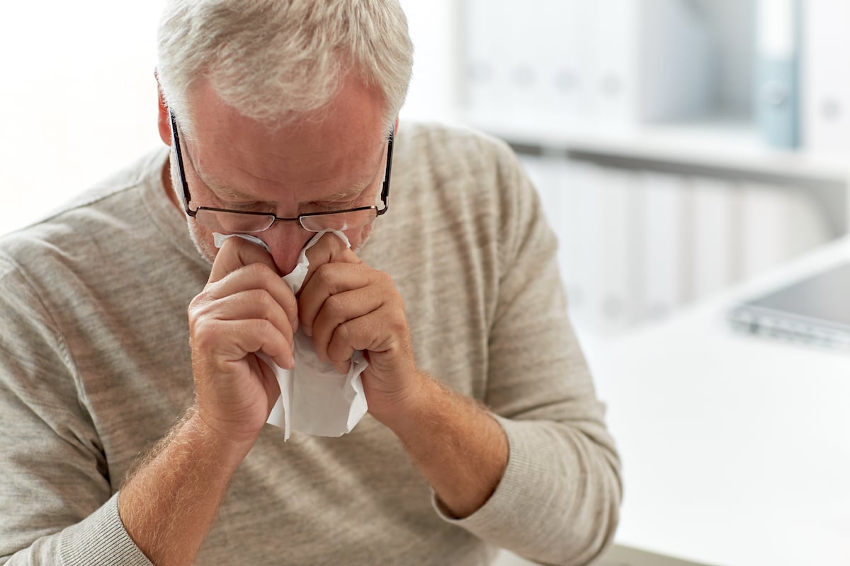 senior-man-blowing-nose-with-napkin-at-hospital-PKNY9ZW